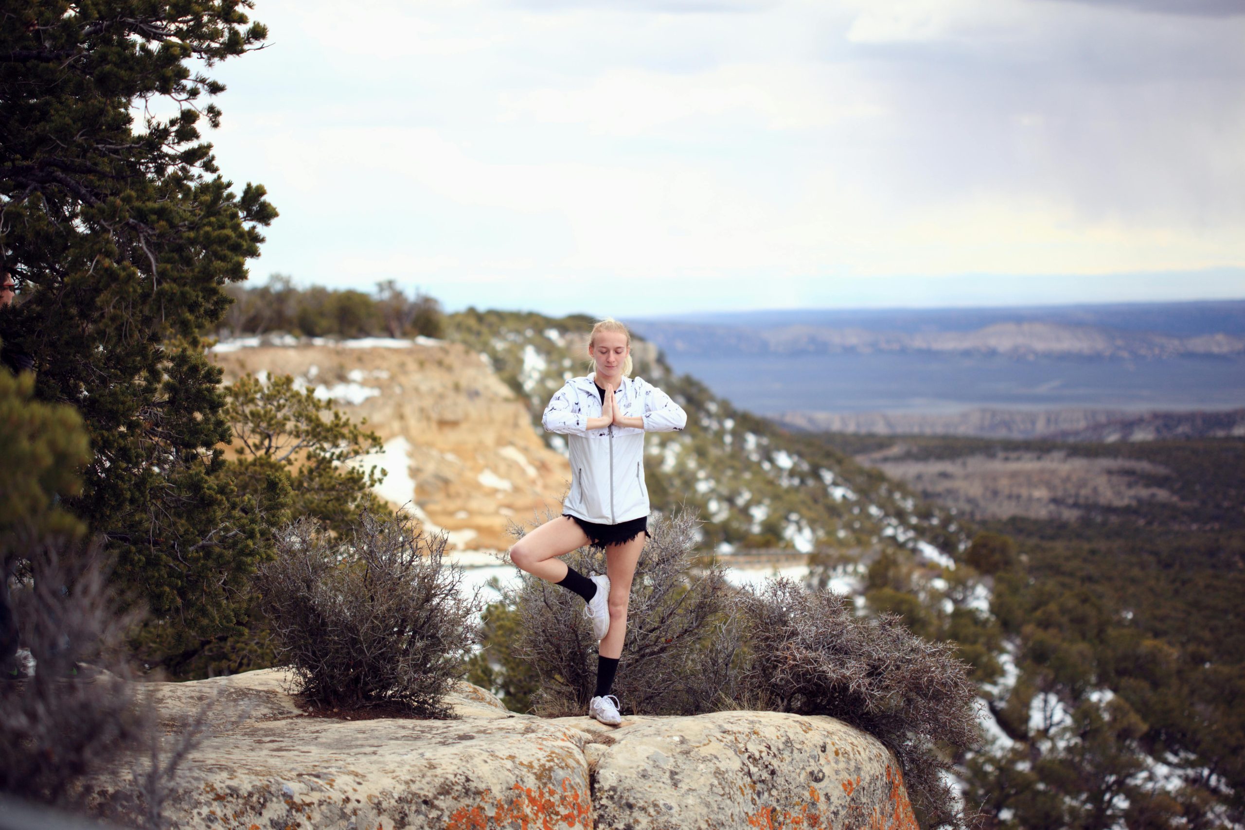 Woman practicing yoga on a cliff in Jensen, Utah with a serene mountain backdrop.