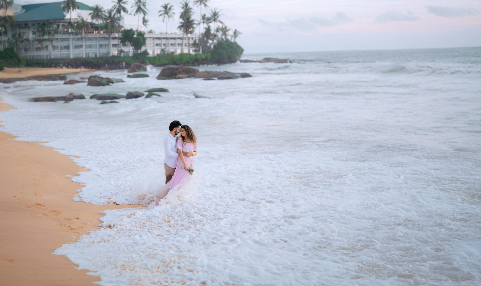 A couple embraces on a picturesque beach in Sri Lanka during a dreamy sunset wedding.