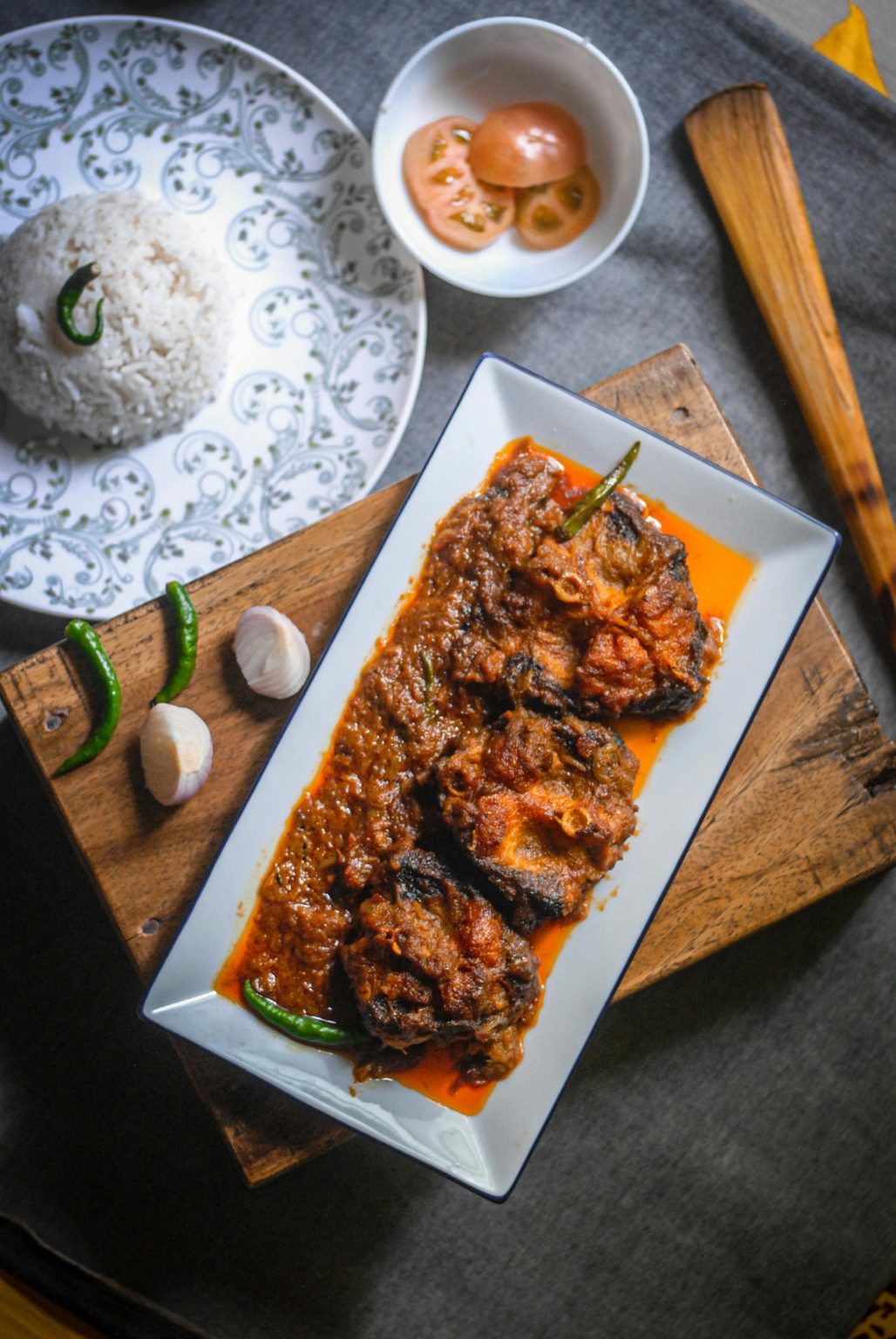 Delicious spicy fish curry paired with steamed rice, garnished with herbs and vegetables, perfect for food photography.